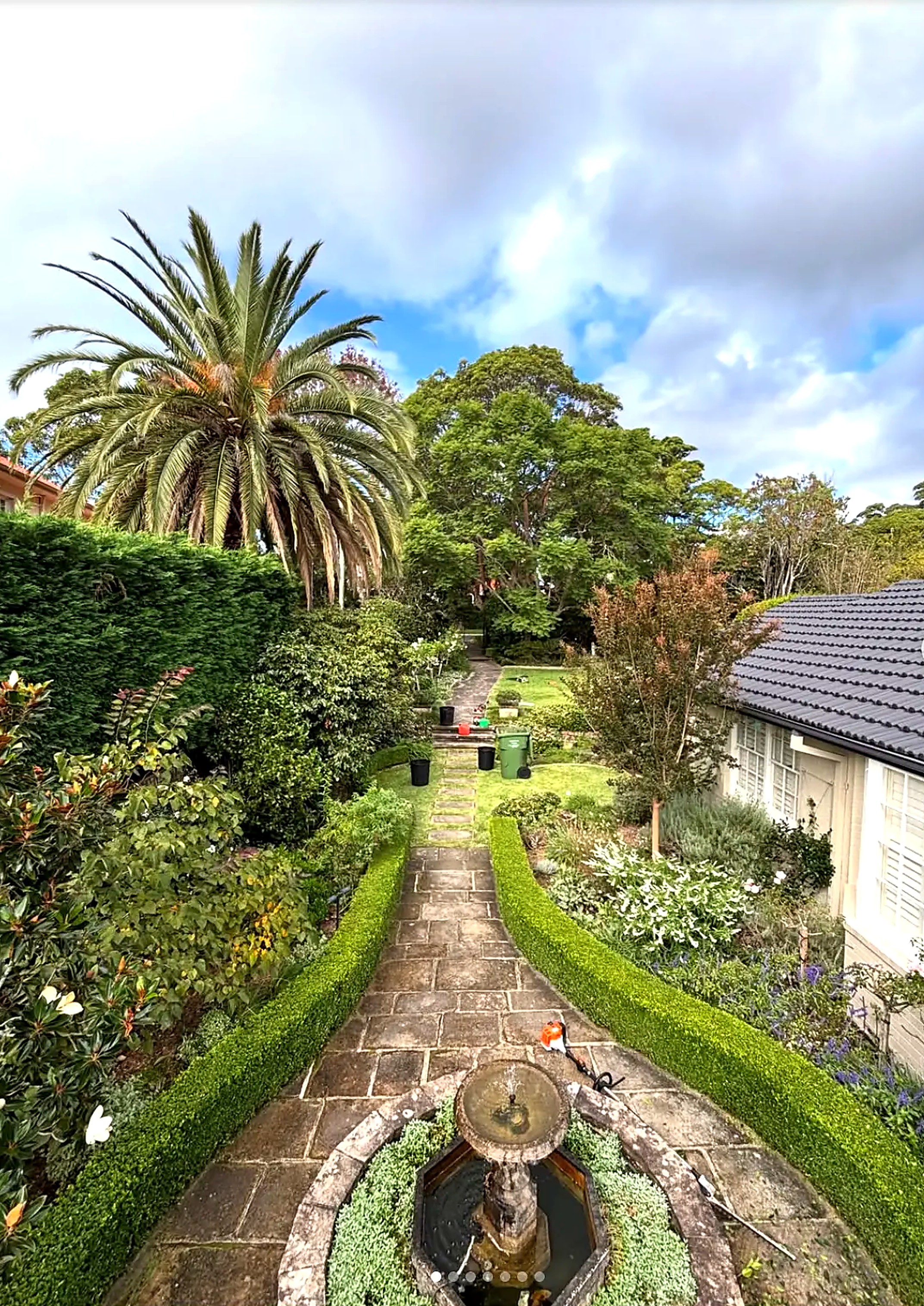 Sandstone path with clipped borders leading to a garden fountain